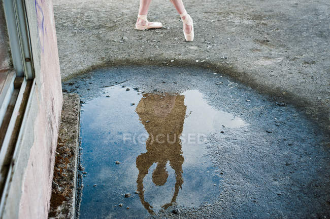 Reflection of ballerina dancing in a puddle — Stock Photo