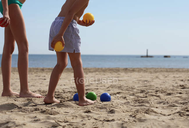 Niño y niña jugando petanca en la playa - foto de stock