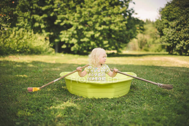 Chica sentada en un bote de remos en el jardín - foto de stock
