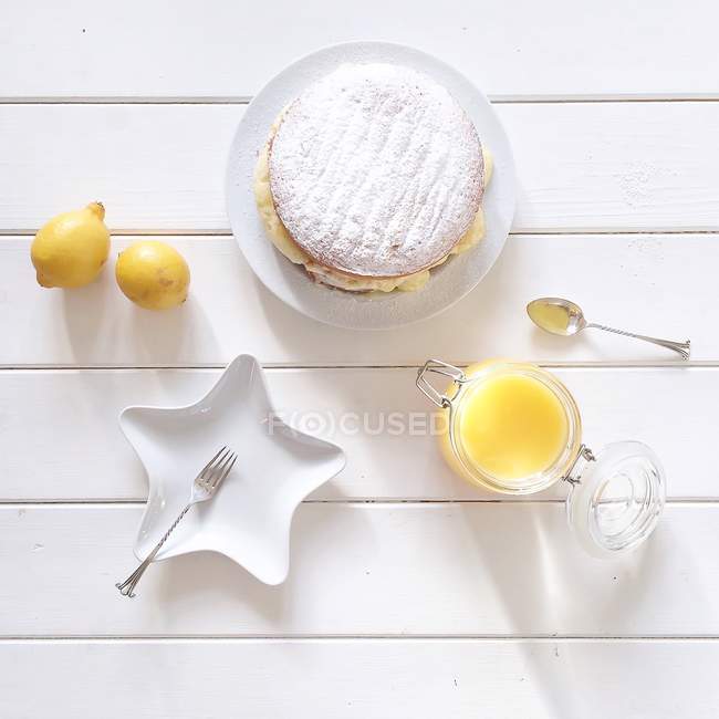 Lemon cake with lemon curd and lemons on white wooden table — Stock Photo