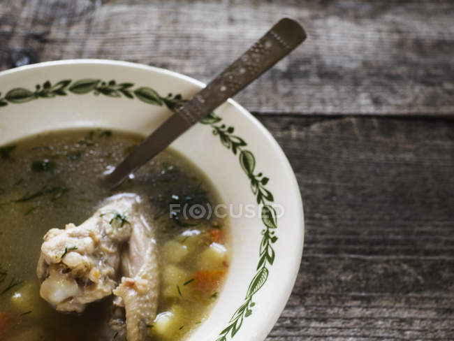 Bowl of chicken soup on wooden table, rustic kitchen — Stock Photo