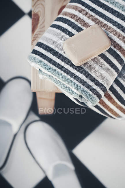 Sapone su asciugamani e pantofole in un bagno — Foto stock