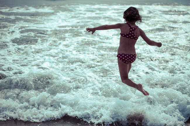 Kleines Mädchen läuft mit Wellen ins Meer — Stockfoto
