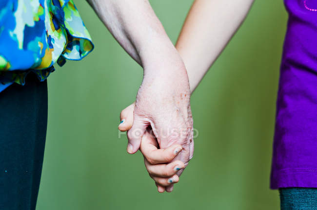 Image recadrée de grand-mère et petite-fille tenant la main sur un fond flou — Photo de stock