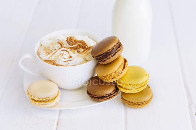 Macarons, lait et tasse de café sur fond de bois — Photo de stock