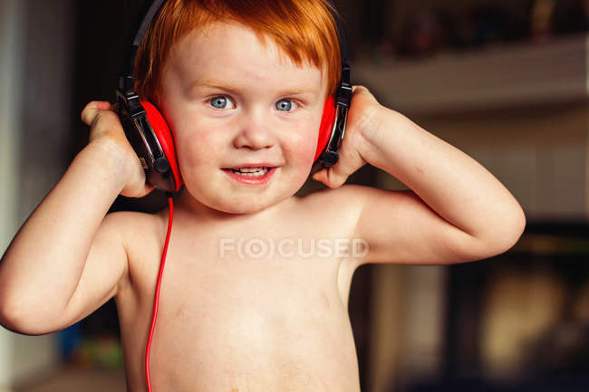 Sorridente ragazzo rossiccio ascoltare musica con le cuffie — Foto stock