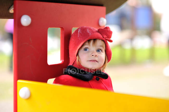Chica con sombrero rojo sentado en una casita de juegos - foto de stock