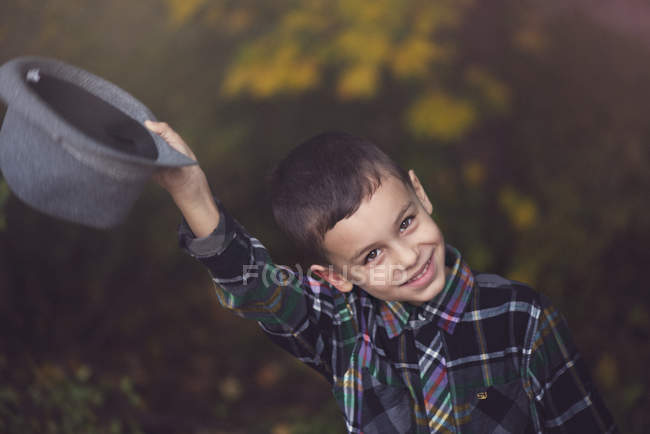 Lächelnder kleiner Junge zieht draußen seinen Hut — Stockfoto