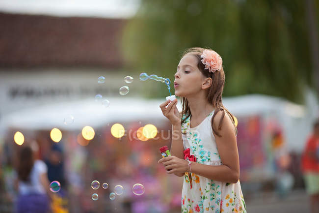 Menina vestindo vestido soprando bolhas de sabão — Fotografia de Stock