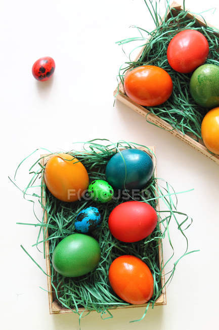 Різнокольорові великодні яйця на штучній траві в коробках — стокове фото