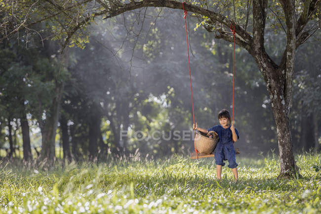 Girl sitting on swing with dog in nature — Stock Photo
