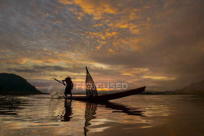 Silhouette di un uomo che pesca sulla barca tradizionale, Lago Bangpra, Thailandia — Foto stock