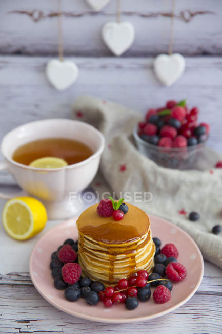 Stack of blueberry pancakes on a plate with blueberries, raspberries and redcurrants — Stock Photo
