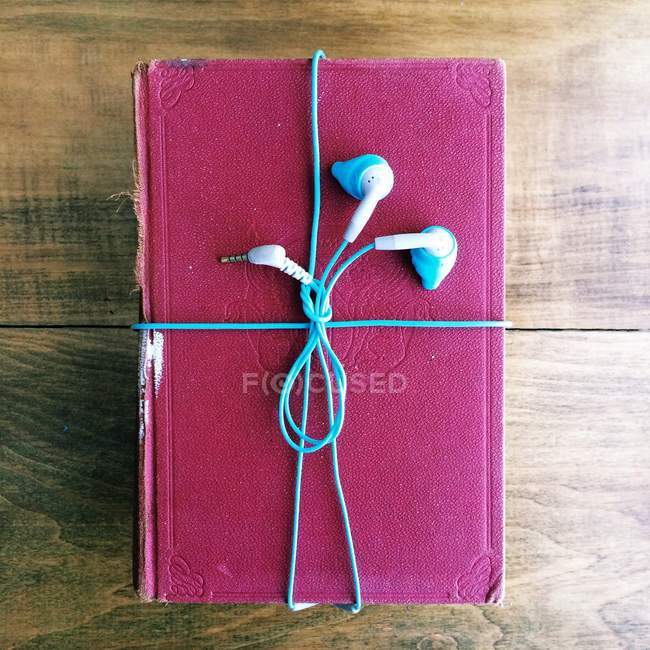 Hörbuchkonzept, Kopfhörer um ein altes Buch gewickelt — Stockfoto