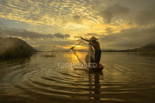 Silhueta de um homem jogando rede de pesca, Lago Bangpra, Tailândia — Fotografia de Stock
