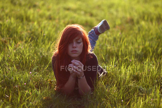 Молода жінка з закритими очима лежить у траві — стокове фото