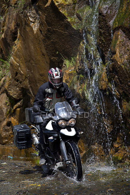 Homme à moto sous la cascade — Photo de stock
