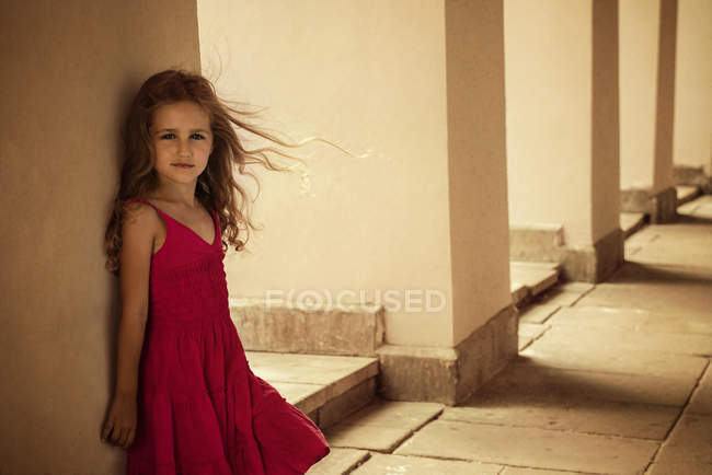 Girl posing in red dress in front of wall — Stock Photo