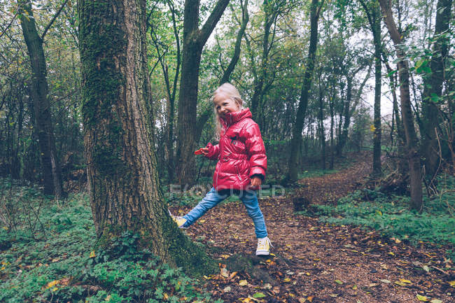 Menina vestindo jaqueta rosa empurrando árvore na floresta — Fotografia de Stock