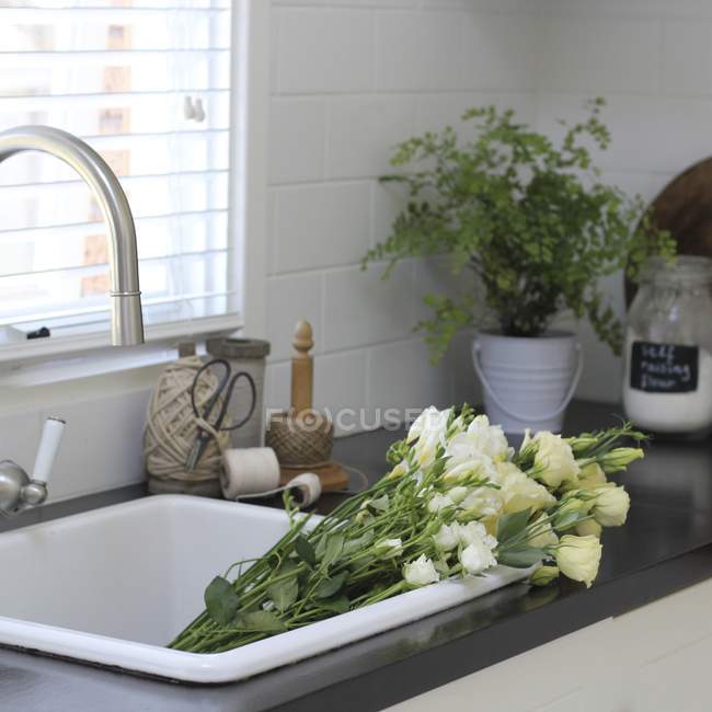Bando de belas flores brancas na pia da cozinha — Fotografia de Stock