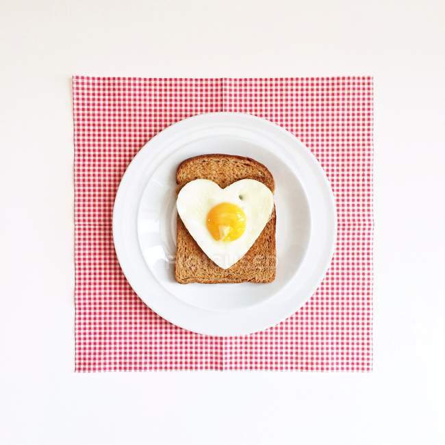 Heart shaped egg on slice of toast, top view — Stock Photo