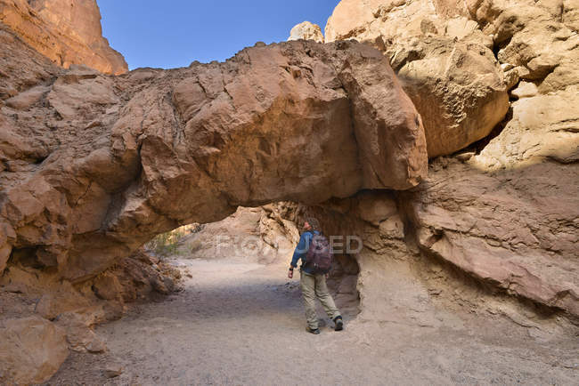 Estados Unidos, California, Parque Estatal del Desierto de Anza-Borrego, Senderista caminando por debajo de un puente natural - foto de stock