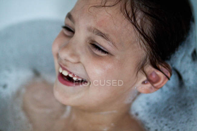 Close-up portrait of smiling little girl taking bath — Stock Photo