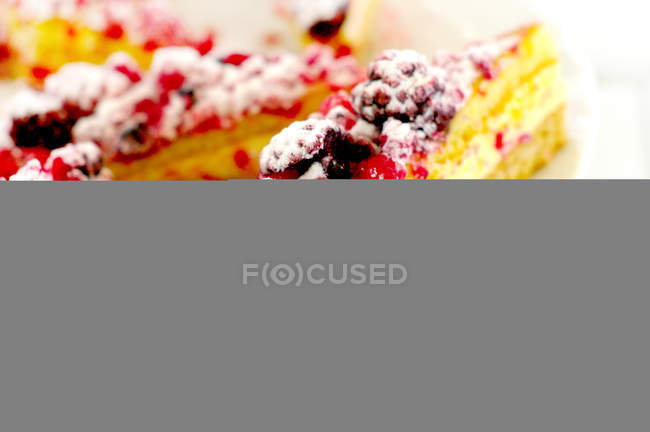 Primer plano de pastel en rodajas con moras y frambuesas en el plato - foto de stock