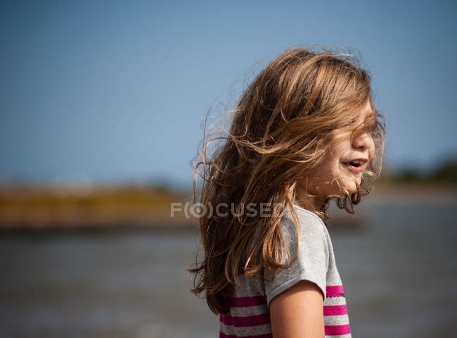 Ritratto di una ragazza con i capelli spazzati dal vento in piedi su strada — Foto stock