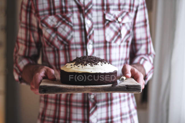 Primo piano di uomo che trasporta torta al cioccolato su tavola di legno — Foto stock