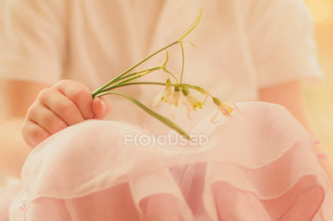 Mädchen in pinkfarbener Kleidung mit Schneeglöckchen in der Mitte — Stockfoto