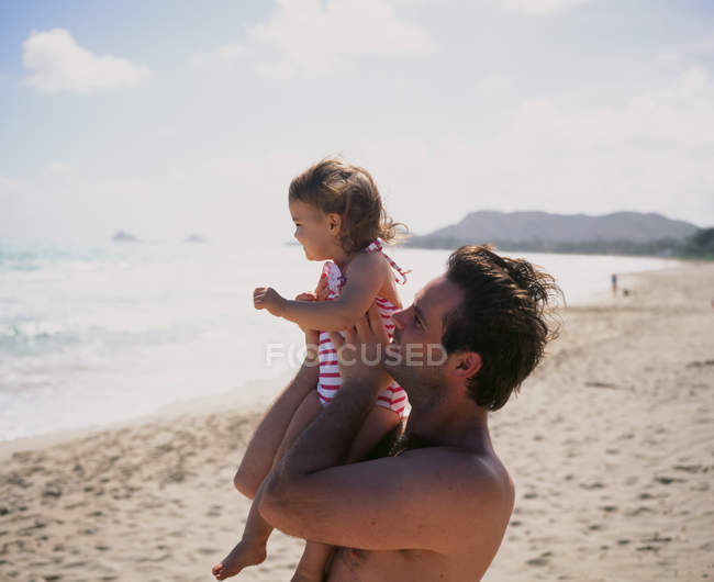 Чоловік з дочкою розслабляється на пляжі — стокове фото