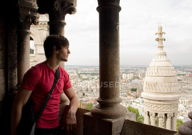 Мужчина стоит на балконе и смотрит на город — стоковое фото