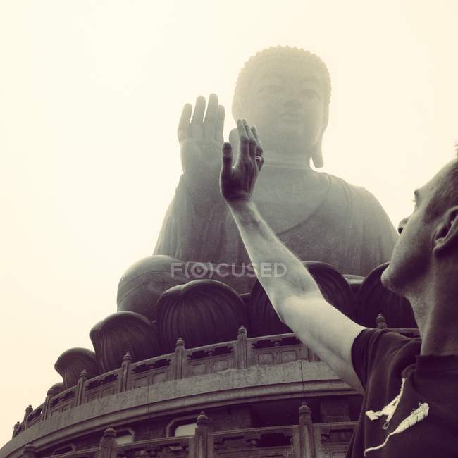 China, Hong Kong, Man giving high-five to Buddha statue — Stock Photo