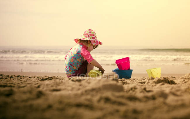 Маленькая девочка играет на песке на пляже — стоковое фото