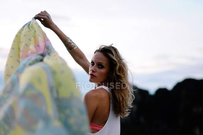 Woman holding sarong in wind on beach — Stock Photo