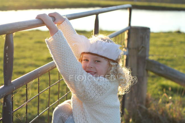 Souriante fille tenant sur la clôture — Photo de stock