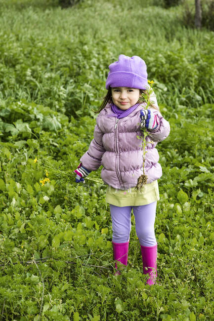Portrait de petite fille tenant cueilli des fleurs sauvages en plein air — Photo de stock