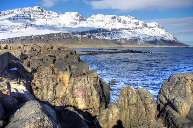 Снігові гори з гігантські скелі на передньому плані, Ісландія — стокове фото