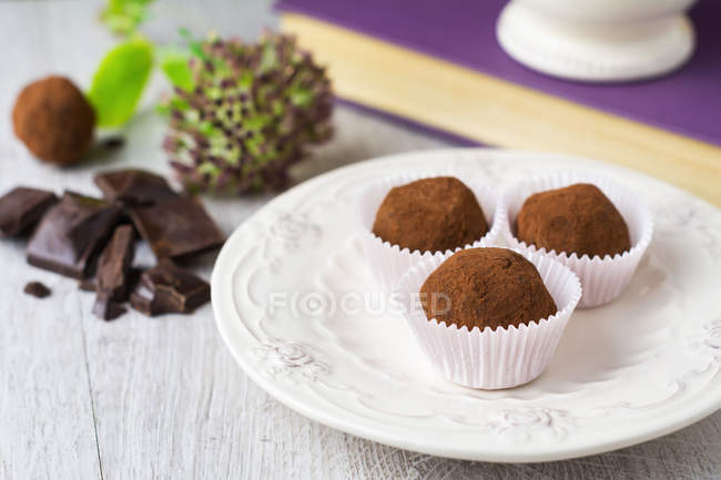 Three chocolate truffles on white plate — Stock Photo