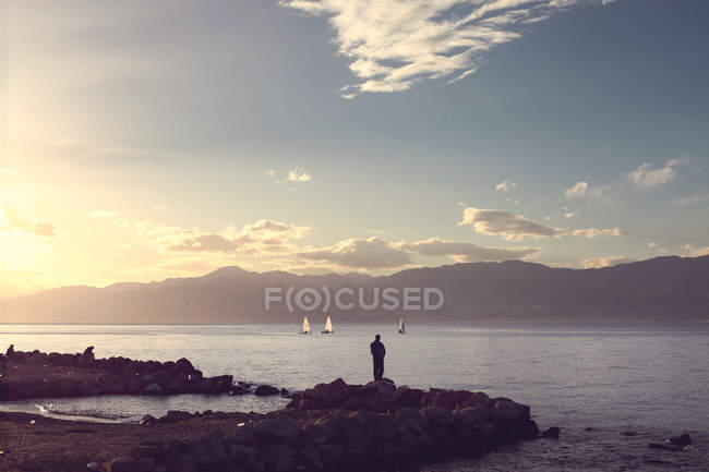 Vista posteriore della silhouette del pescatore sulla costa — Foto stock