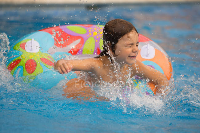 Дівчина в басейні бризкає в надувному кільці — стокове фото