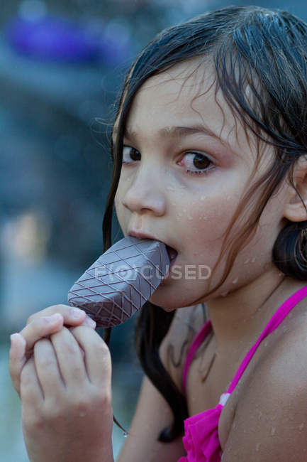 Close-up portrait of beautiful girl with wet hair eating ice cream and looking at camera — Stock Photo