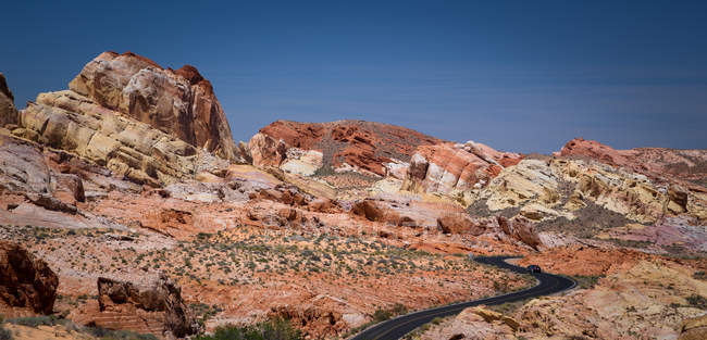 Coche solitario en carretera curva en Valley o Fire State Park, Nevada, EE.UU. - foto de stock