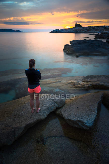 Francia, Córcega, Mujer viendo atardecer en la playa - foto de stock