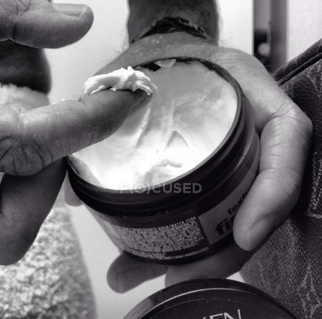 Cropped image of male hands holding hair gel, monochrome — Stock Photo