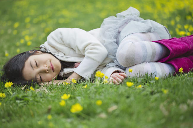Chica acostada en la hierba con los ojos cerrados - foto de stock