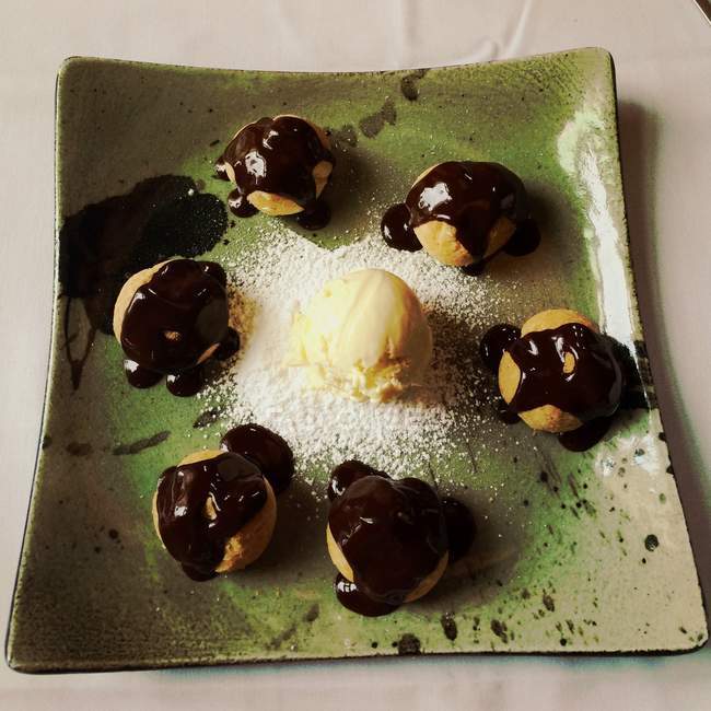Elevated view of sweet and tasty profiteroles on green ceramic plate — Stock Photo