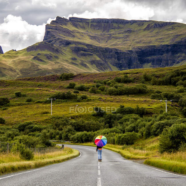 Вид сзади женщины с пумбраной на проселочной дороге, Шотландия, Великобритания — стоковое фото