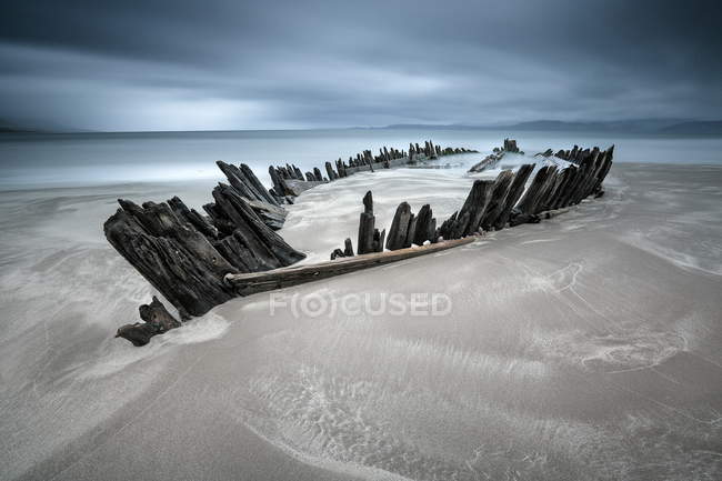 Irlanda, Kerry, Rossbeigh Strand, Restos de bote de remos de madera en arena de playa - foto de stock